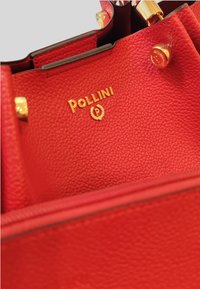 Borsa a mano in pelle rossa con superficie texturizzata, hardware dorato e logo 'Pollini' in rilievo. L'interno presenta una fodera liscia con zip.