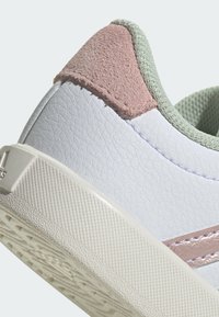 Sneaker bianca in pelle con accentuazione in suede rosa sul tallone e dettagli testurizzati verde chiaro. Presenta una suola in gomma con una presa rigata.