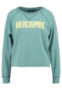 Zielony krótki sweatshirt wykonany z miękkiego materiału. Na przodzie widnieje żółty napis "ABERCROMBIE", a na rękawie biały tekst. Żebrowane mankiety.