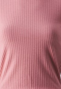 Rippendes, enganliegendes Oberteil aus softem pinkfarbenem Stoff. Verfügt über vertikale Streifen und ein figurbetontes Design, das die Textur betont, ohne zusätzliche Verzierungen.