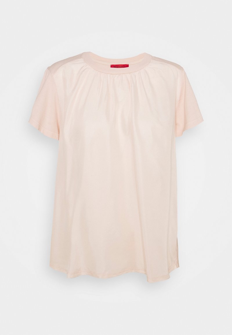 Blouse beige clair à manches courtes avec encolure froncée et tissu lisse, présentée sur un fond blanc uni.
