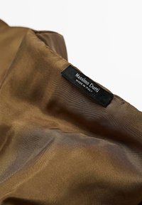 Tessuto in satin marrone con una texture liscia, caratterizzato da un'etichetta nera che riporta "Massimo Dutti" e "FABBRICATO IN ITALIA."