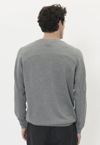 Sudadera gris con mangas largas, cuello redondeado y tejido texturizado. Presenta un diseño limpio en la parte posterior con detalles en las costuras de los hombros.