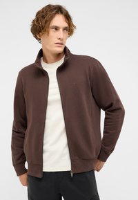 Brown zip-up jacket made from soft material, featuring a high collar, ribbed cuffs, and a small logo on the upper left side.