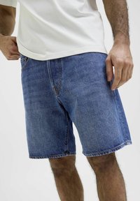 Shorts in denim blu, con un taglio classico e gambe dritte, cinque tasche e cuciture a contrasto lungo le cuciture.