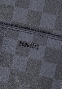 Černá peněženka z umělé kůže s kostičkovým vzorem, výrazným raženým logem „JOOP!“ a hladkou texturou s prošitými okraji.