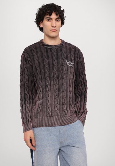 Pull en tricot à motif texturé, en dégradé de nuances de marron et de violet. Il présente un col et un ourlet côtelés, avec le logo brodé "KidSuper Studios".