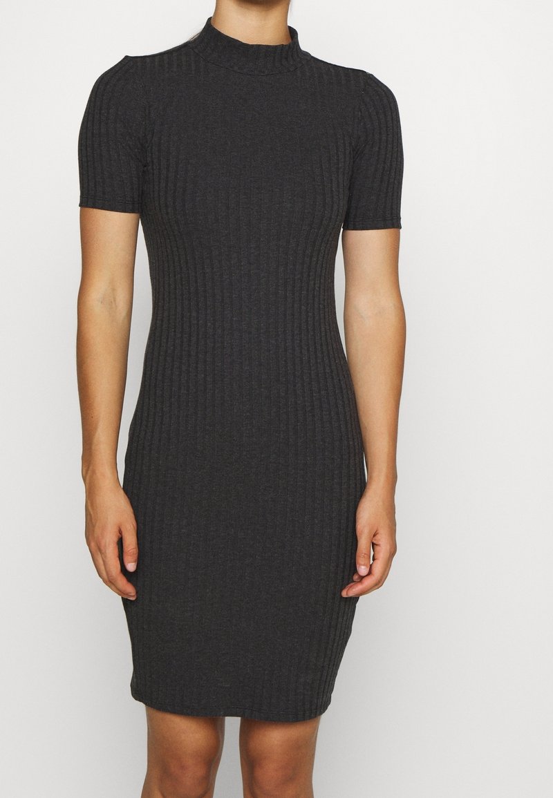 Robe ajustée en maille côtelée gris charbon avec manches courtes et col montant, portée par une personne debout sur un fond uni.