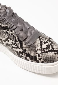 Gray and black snake-patterned sneaker with glossy texture, oversized satin laces, and white textured rubber sole.