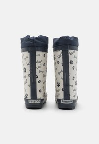 Bottes de pluie en caoutchouc avec un haut marine, présentant un corps crème décoré de traces de pattes noires et d'os, marqué "FRIBOO" à l'arrière.