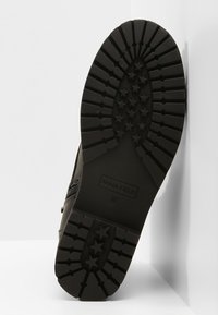 Černá gumová podešev boty s texturovaným vzorem vzorku obsahujícím hvězdy, označená "ANNA FIELD" a velikostí "37". Hladký, pevný boční materiál.