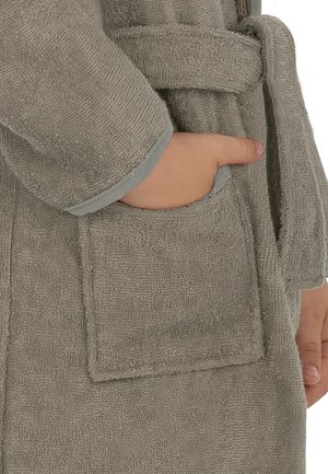 Hand eines Kindes in der Vordertasche eines grauen Frotteebademantels mit gebundenem Gürtel.