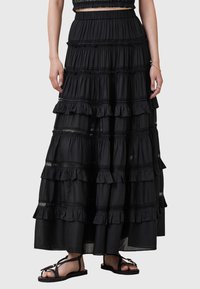 Jupe maxi noire à volants en tissu léger, avec des couches froncées et des accents en dentelle. Équipée d'une taille élastique pour un confort optimal.