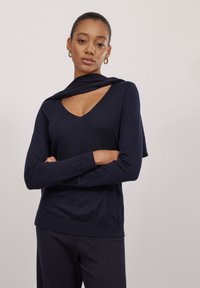 Marineblaues Langarmshirt mit V-Ausschnitt, raffiniertem Kragen und geripptem Saum. Hergestellt aus weichem Stoff, bietet es eine lockere Passform und eine glatte Textur.