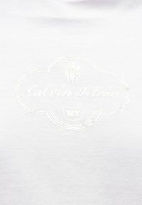 Λευκό βαμβακερό μπλουζάκι με ανάγλυφο λευκό κεντημένο λογότυπο "Calvin Klein" και "NY" σε σχήμα σύννεφου.