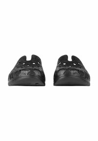 Scarpe slip-on nere realizzate in materiale flessibile, con motivi circolari ritagliati e una suola bassa e sagomata per una facile calzata.