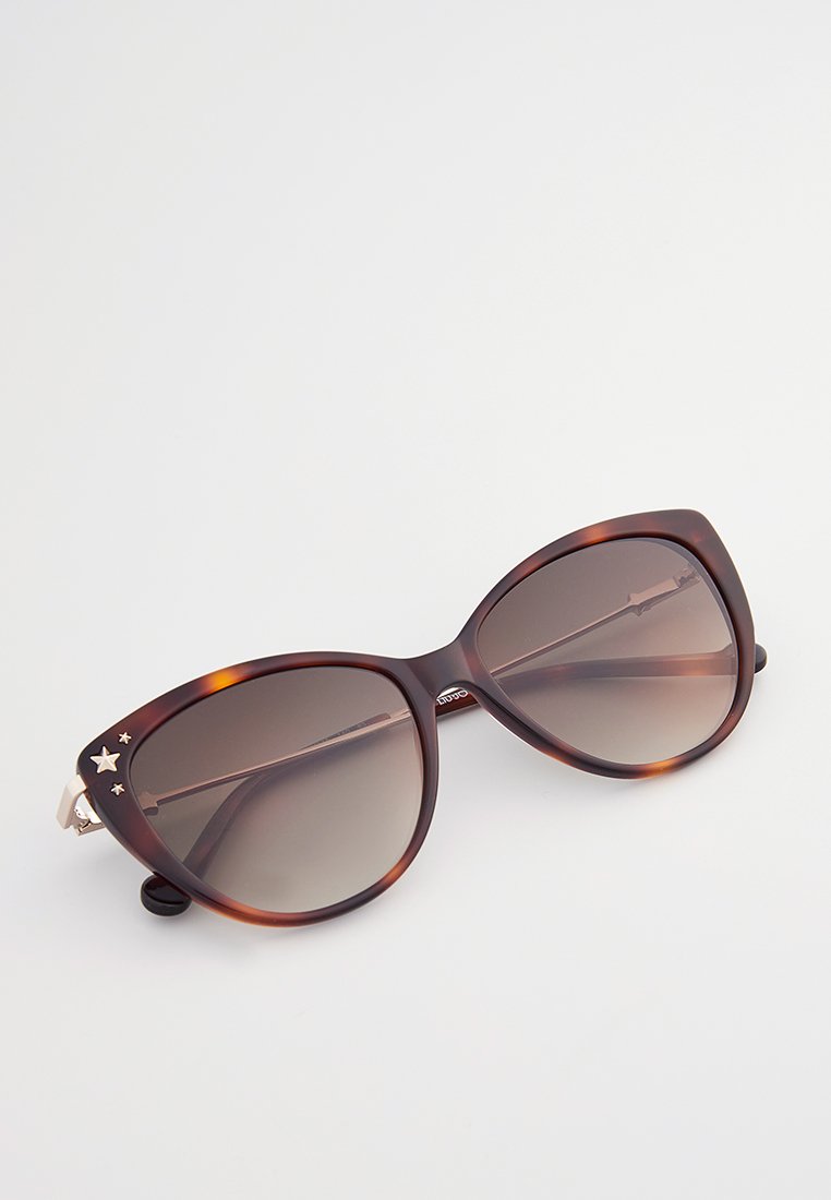 Lunettes de soleil en écaille de tortue avec de grandes montures en forme d'œil de chat, verres dégradés marron et accents en étoile dorés sur les tempes.