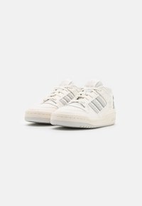 Białe sneakersy z gładką skórzaną cholewką, z pamiętającymi srebrne pasy po bokach i teksturowaną gumową podeszwą.