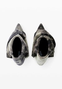 Zapatos de tela a rayas con un diseño de punta afilada y un upper doblado. Los colores incluyen negro y crema con un acabado texturizado.