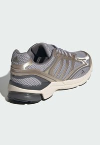 Gray athletic shoe with mesh upper, metallic accents, contouring design, and rubber sole. Features laces and padded collar for comfort.