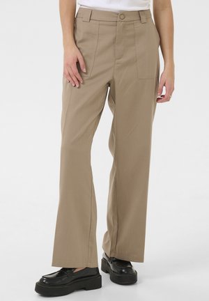 Beige wide-leg pants with a high waist, front pockets, and a smooth fabric texture, paired with black platform shoes.