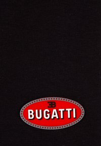 Logo oval rojo de Bugatti con letras blancas y borde negro sobre un fondo de tela negra.
