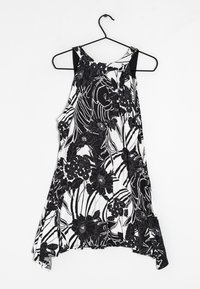 Débardeur floral noir et blanc avec une coupe ample, doté d'un large décolleté et d'un ourlet asymétrique. Tissu lisse avec un motif floral détaillé.