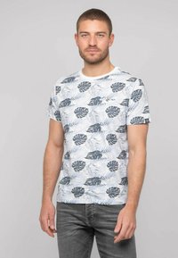 T-shirt à manches courtes en coton blanc, avec des motifs de feuilles vertes et bleues. Col rond avec une coupe décontractée et sans matériel visible.