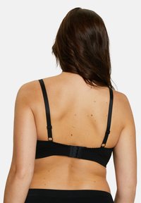 Soutien-gorge noir avec bretelles réglables, tissu texturé, système de fermeture à crochets et œillets, et bordure en V sur le band et les bords des bretelles.