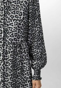 Kleidi leopardiku mustriga hallil taustal, millel on mustad laigud. Pikad varrukad kogutud mansettidega ja laienev seelik. Pehme kangastekstuuri.