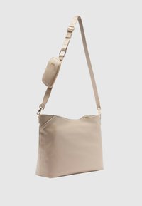 Borsa a spalla beige con superficie liscia e texture, dotata di una lunga tracolla regolabile e di una piccola tasca con zip attaccata.