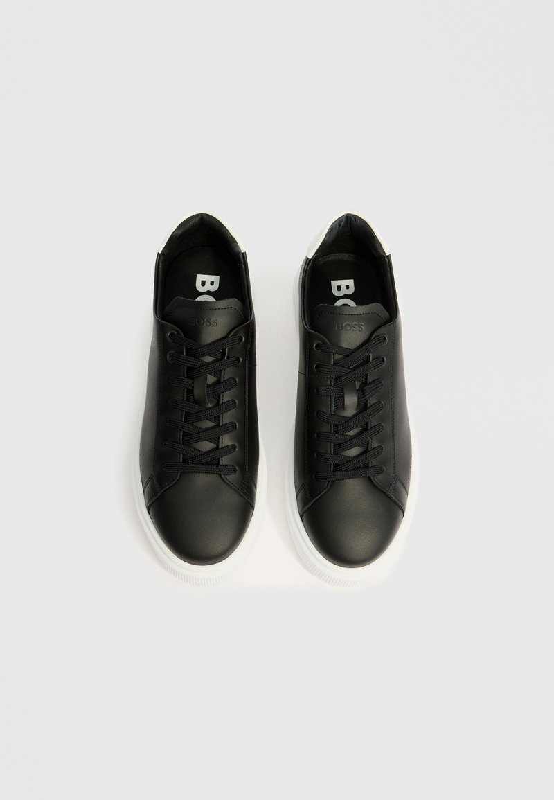Baskets en cuir noir avec une texture lisse, dotées de lacets plats noirs, d'une semelle en caoutchouc blanche et du logo "BOSS" à l'intérieur.