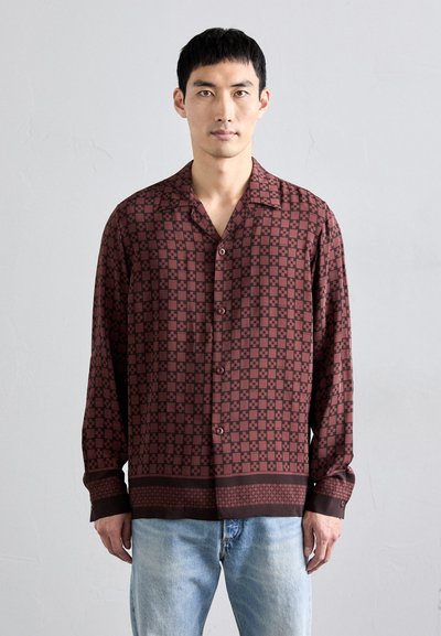 Brown patterned button-up shirt with a relaxed fit, long sleeves, and a contrasting hem design. Made of smooth fabric.