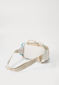 Kleine rechthoekige beige en blauwe schoudertas met een gevoerde achterpaneel en verstelbare schouderband, gelegd op een witte ondergrond.