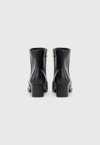 Czarne skórzane botki za kostkę z kwadratowym obcasem, bocznymi suwakami i gładką fakturą. Minimalistyczny design z prostymi liniami i bez widocznych wzorów.