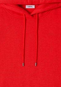 Sudadera con capucha roja, fabricada en un tejido suave, que presenta cordones con puntas de metal y un logotipo en relieve en el frente.