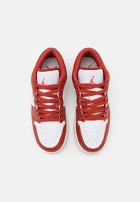 Rode en witte leren sneakers met geperforeerde neus, platte veters en een logo op de tong. Rond neusje en ontwerp met gevoerde kraag.