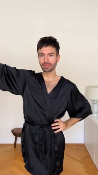 Fekete selymes köntös széles ujakkal, övvel ellátott derékkal és egyszerű V-nyakkivágással. Simaság és elegáns redők.