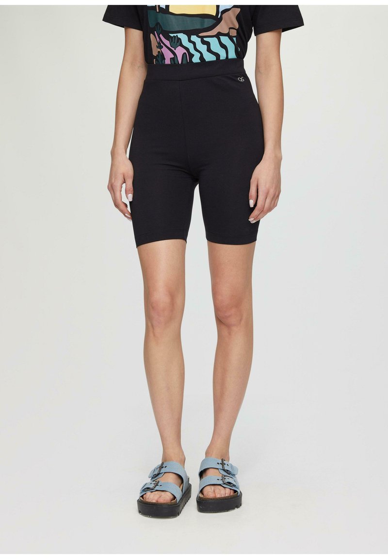 Shorts de vélo noirs à taille haute, texture lisse, associés à des sandales bleues avec des sangles à boucle et une semelle épaisse.