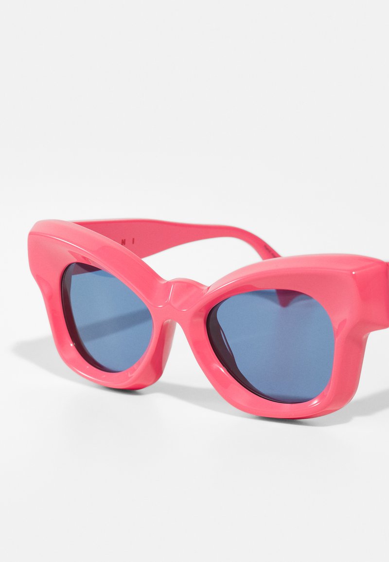 Gafas de sol de plástico rosa en forma de ojo de gato con lentes teñidos de azul, que presentan un marco grueso y un diseño angular único.