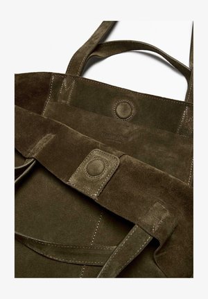 Sac fourre-tout en suède vert olive avec deux poignées, doté d'une fermeture à pression et d'un logo embossé. Texture lisse avec des détails de couture visibles.