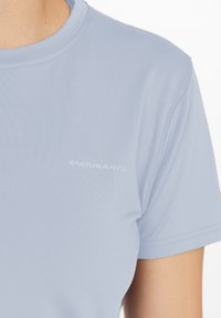 Ljusblå kortärmad sportt-shirt i slätt tyg. Har "ENDURANCE"-logotypen i vitt på framsidan och en rundad halsringning.