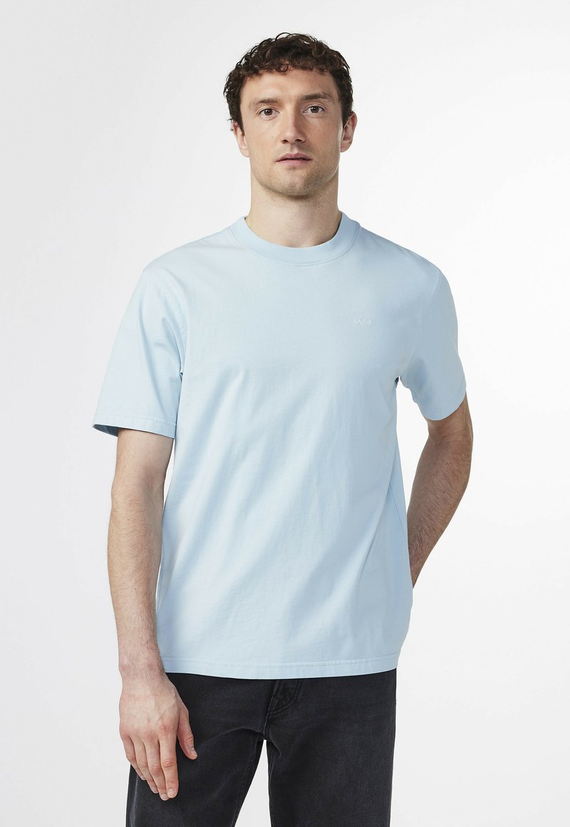 Camiseta de manga corta azul claro, con cuello redondo, hecha de algodón. Presenta un diseño simple con un bordado sutil en el pecho.