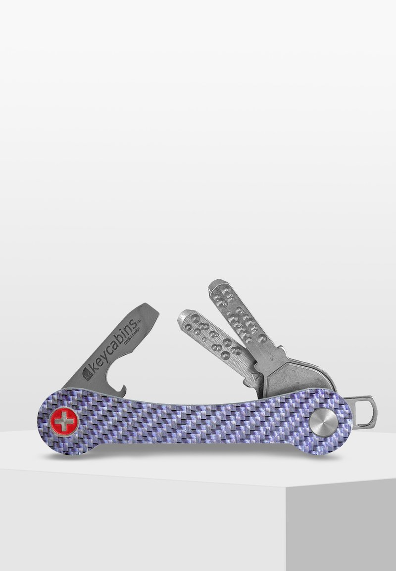 Multiverktyg med handtag i lila kolfiber. Inkluderar metallnycklar och verktyg, med en röd schweizisk kors emblem och silverfärgade detaljer.