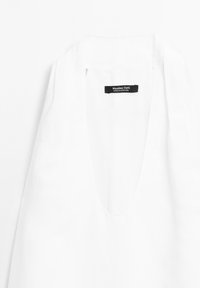 Weißes Leinenoberteil mit tiefem V-Ausschnitt. Verfügt über ein schwarzes Etikett mit dem Text "Massimo Dutti". Schlichte, klare Verarbeitung und glatte Textur.