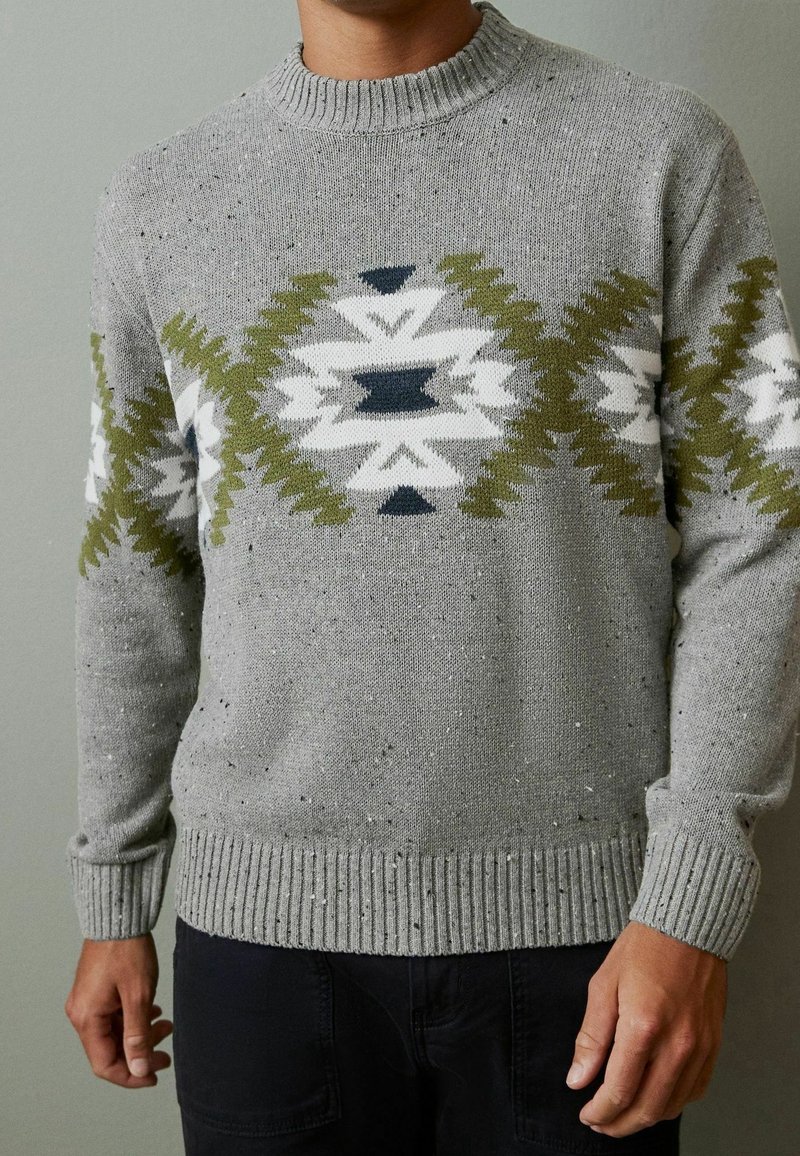 Maglione grigio con motivo geometrico in verde scuro, blu navy e bianco. Tessuto a maglia testurizzato con scollo e polsini a coste.
