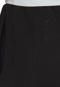 Schwarze Sweatpants mit vertikalen Falten, einem elastischen Bund und dezentem "ALL SZN" Stick auf der Seite in passendem Faden.