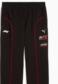 Juodos sportinės kelnės su raudonu apvadu, F1 logotipu, Puma logotipu ir „24/24“ grafika šone. Elastinga juosmens juosta patogumui.