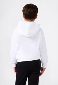 Sudadera blanca con capucha hecha de una tela suave, con puños y dobladillo acanalados. Llevada con pantalones negros, mostrando un diseño limpio y sencillo.