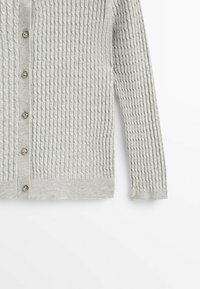 Harmaa neulecardigan, jossa on tekstuurimallinen pinta. Siinä on napitus pyöreillä metallinupeilla sekä ribbauskudokset hihoissa ja helmassa.